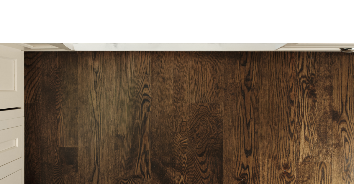 Dark brown wood plank flooring with prominent grain patterns, shown installed against a white wall and baseboard.