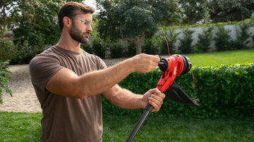 Hombre utilizando la manivela del cabezal Smart Load™ para enrollar el hilo de la orilladora